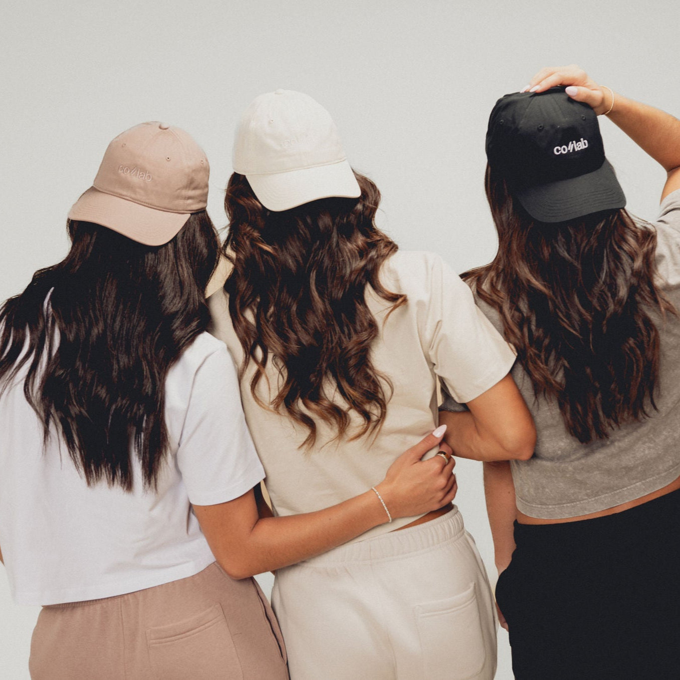 Three women wearing hats with a plain background