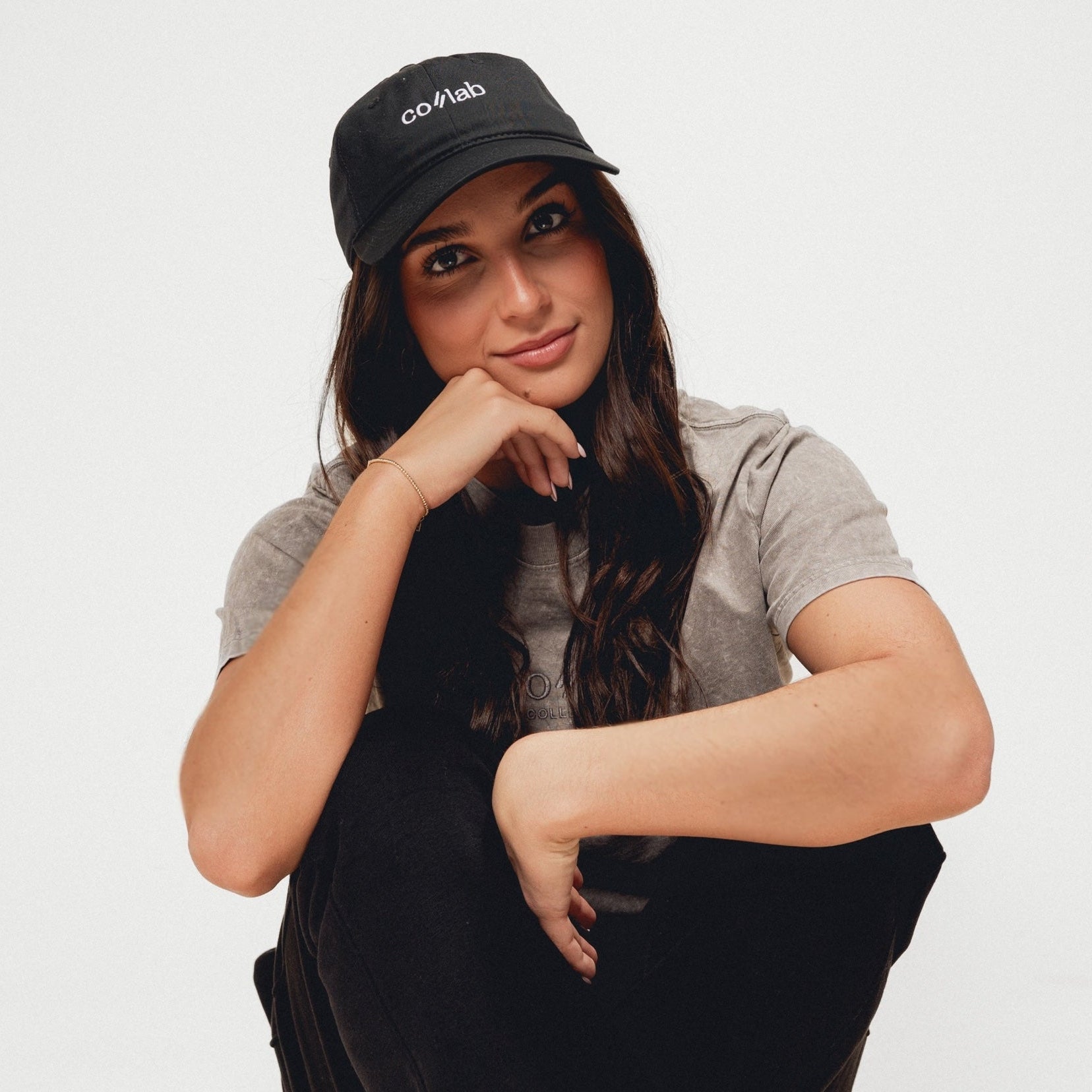 Woman wearing a black cap with visible colab branding on a white background